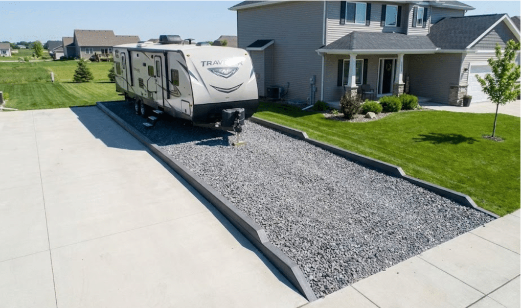 Gravel RV parking pad with 35-foot travel trailer parked beside residential home